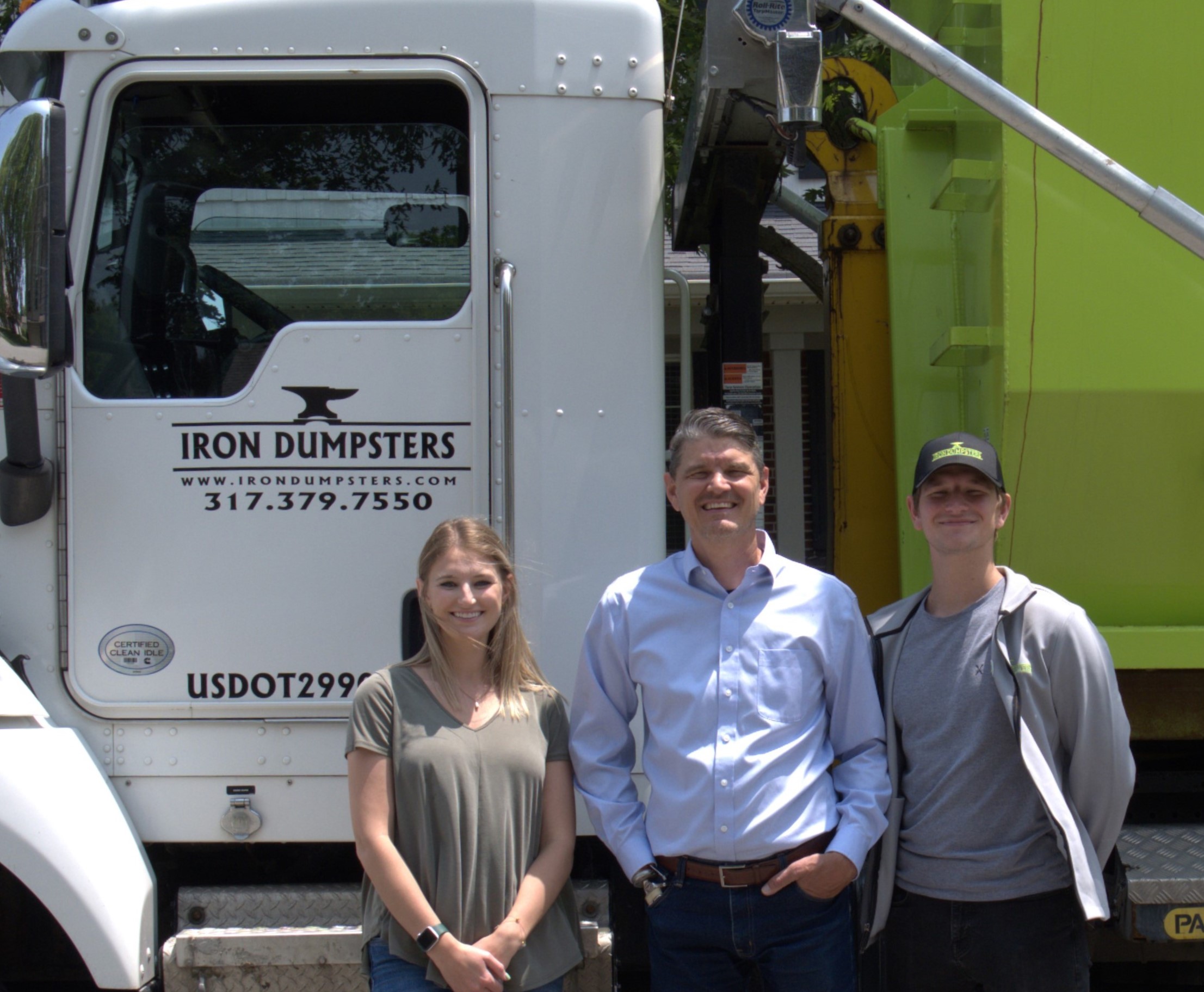 The team posing in front of a dumpster truck.
